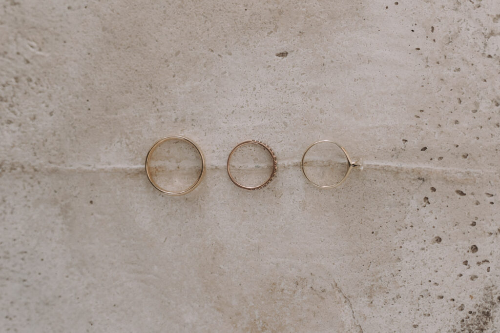Three wedding rings on stone surface – elegant flatlay detail