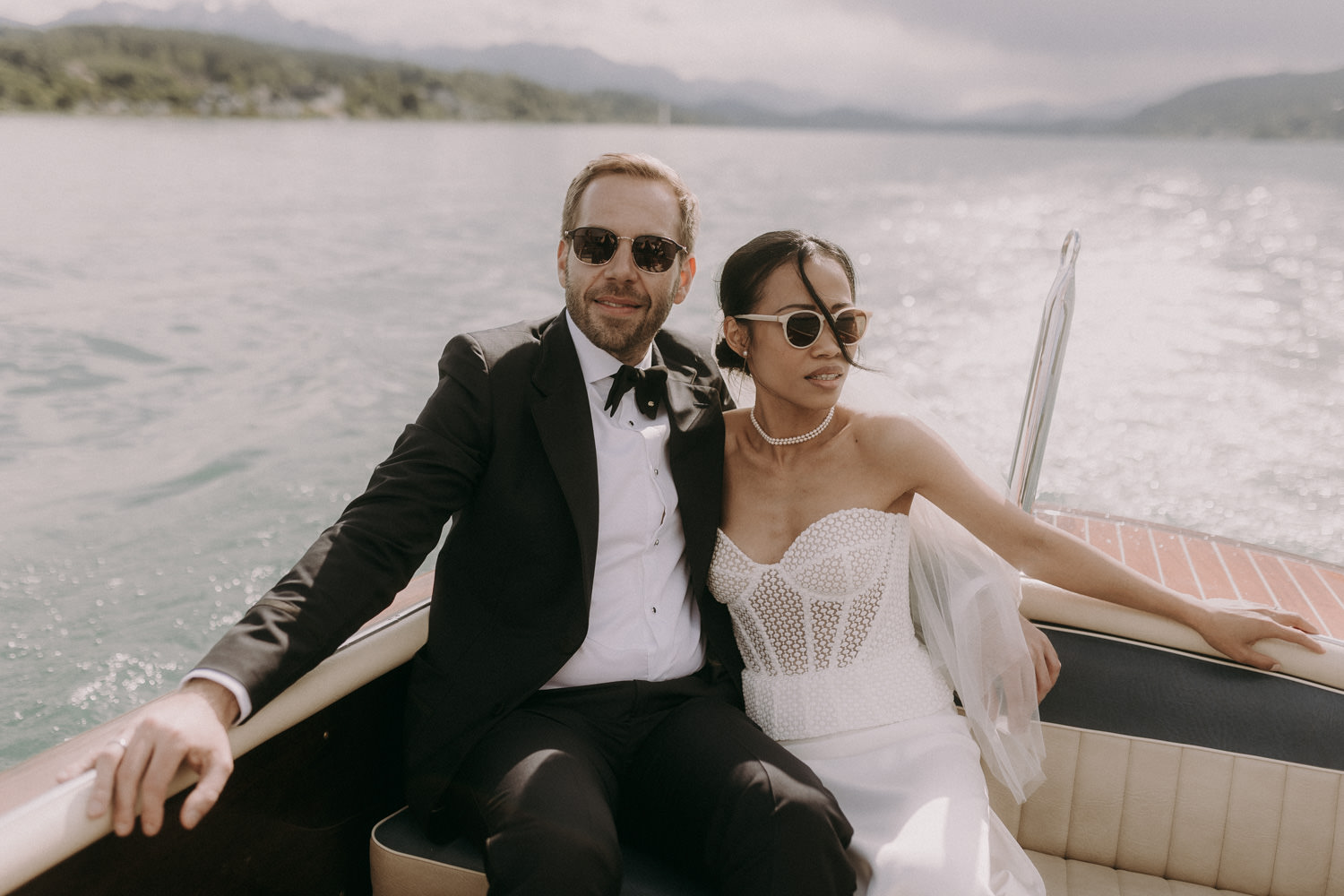 Bride and groom relax on a speedboat after their lake wedding ceremony.