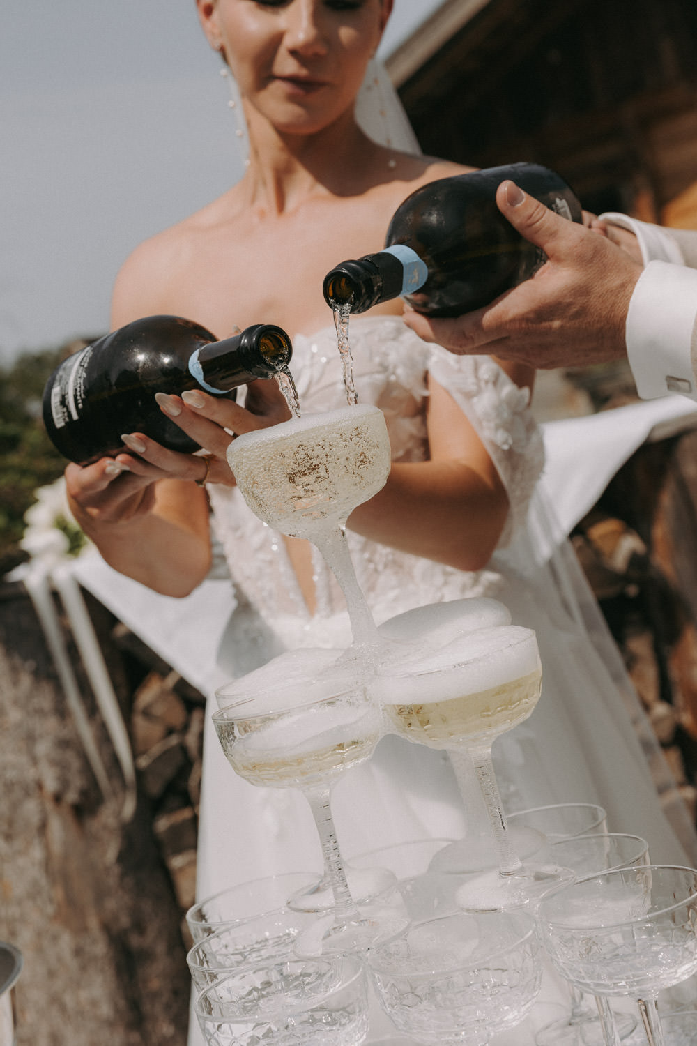 Destination wedding photographer capturing bride pouring champagne into tower of glasses