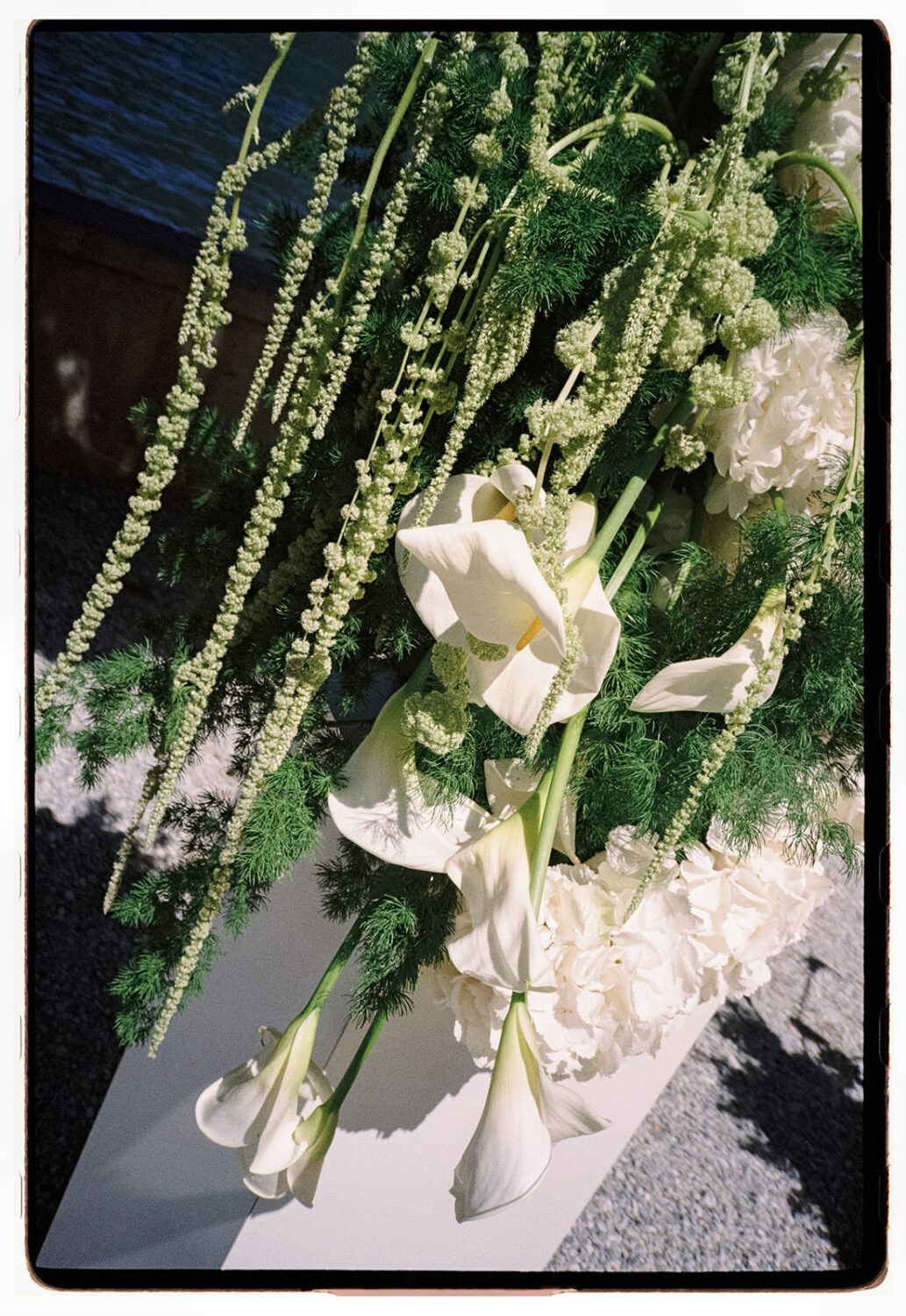 White calla lilies, hydrangeas and hanging amaranthus in a wedding floral arrangement, shot on 35mm film.